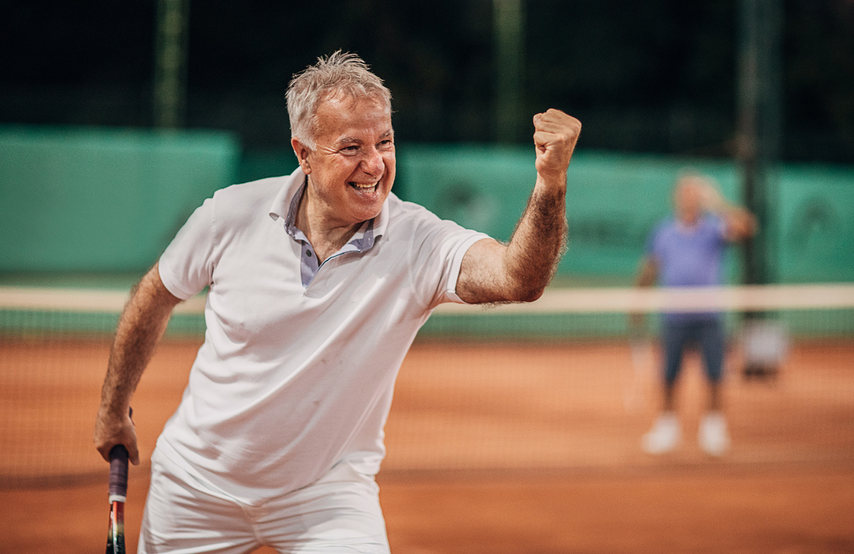 Happy senior man tennis player winning in tennis match